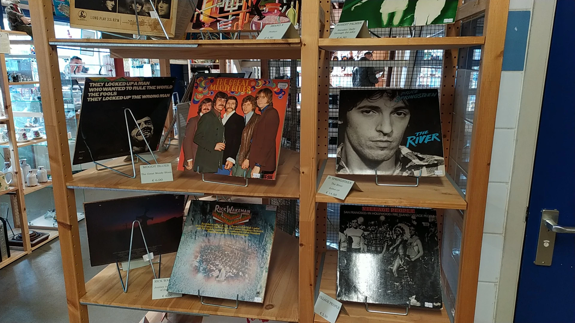 Vitrinekast met vintage LP-platen en albumhoezen uitgestald op houten schappen