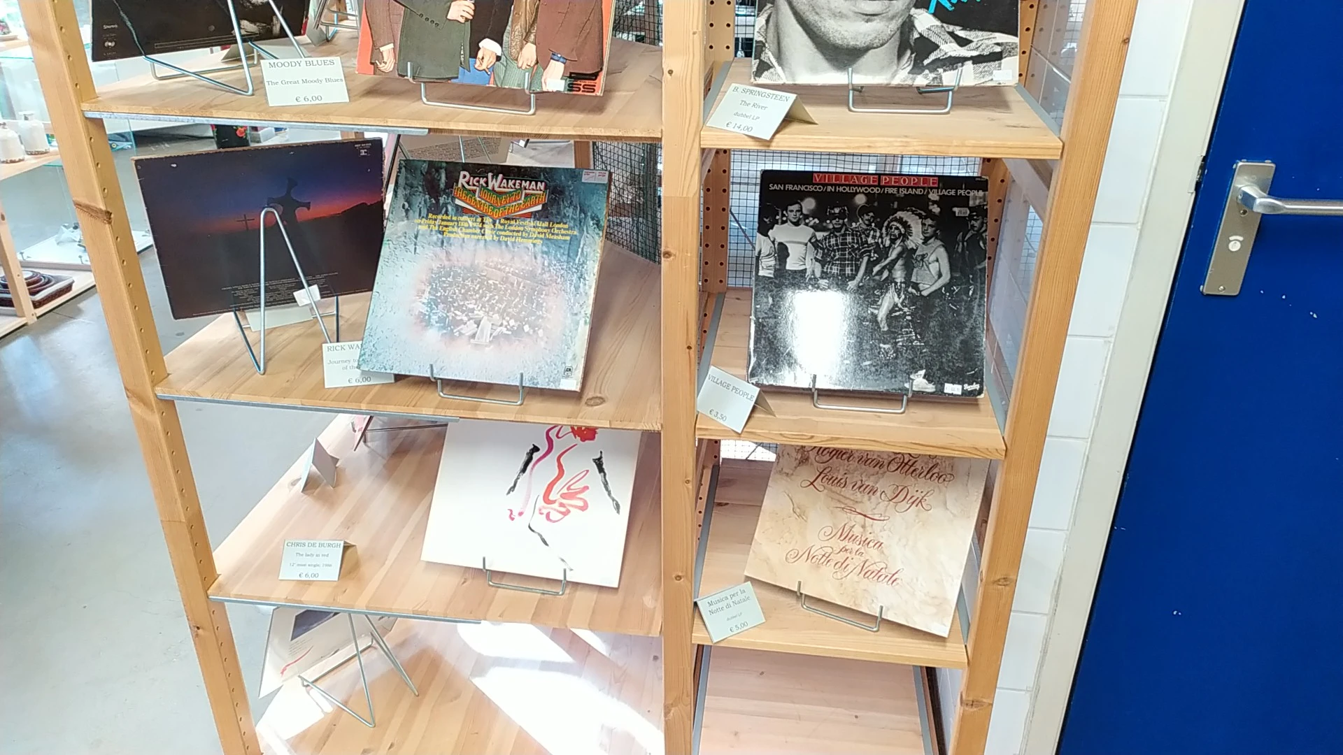 Twee houten stellingen met uitgstalde vinyl records, fotoboeken en muziekalbums