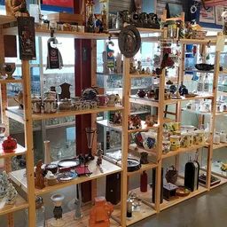 Houten vitrinekasten met uitgestalde decoratieve artikelen, servies, vazen en diverse tweedehandsartikelen in een kringloopwi