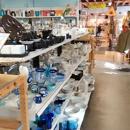 Toonbank met uitgestalde huishoudartikelen: blauwe kunststof servies, glazen en ander keukengerei