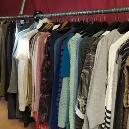 Rekken met diverse tweedehands kleding in verschillende kleuren en stijlen op hangers