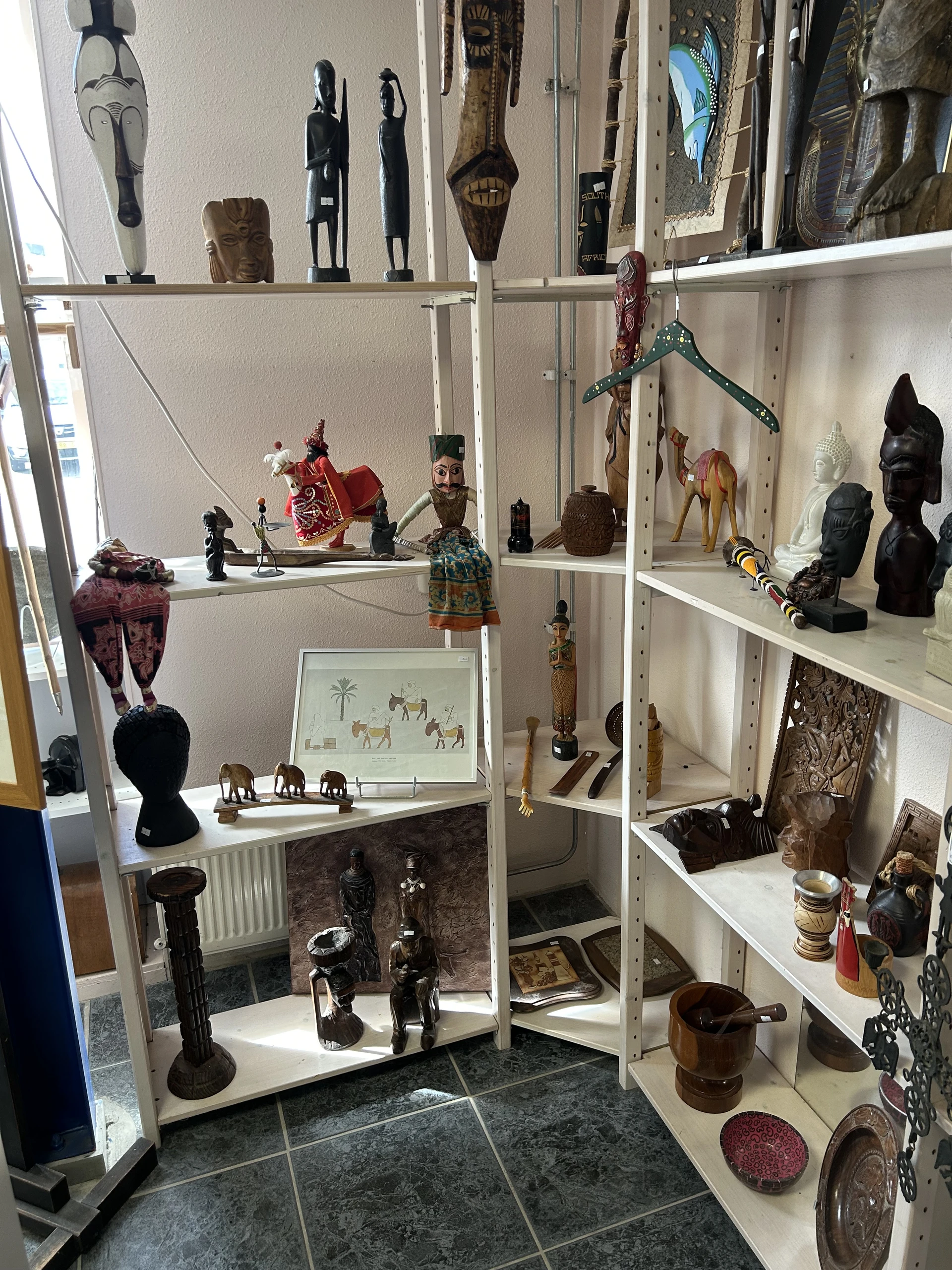 Glazen vitrinekast met decoratieve beeldjes, sculpturen en kunstobjecten uit verschillende culturen en stijlen