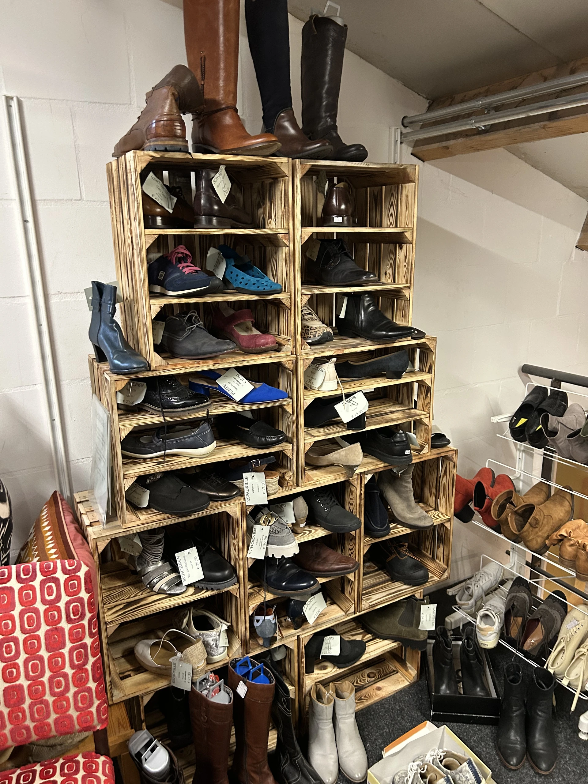 Houten stellingkasten met diverse tweedehands schoenen en laarzen uitgestald op meerdere niveaus