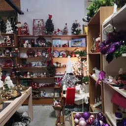 Kerstdecoraties en seizoenartikelen uitgestald op houten stellingen en planken, waaronder rode en paarse versieringen, kerstb