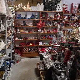 Houten stellingen volgesteld met kerstdecoratie in rood en wit, waaronder kaarsen, figuurjes en versieringen