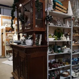 Uitgestalde decoratieve artikelen en huishoudspullen op kasten en een donker houten dressoir in de winkel