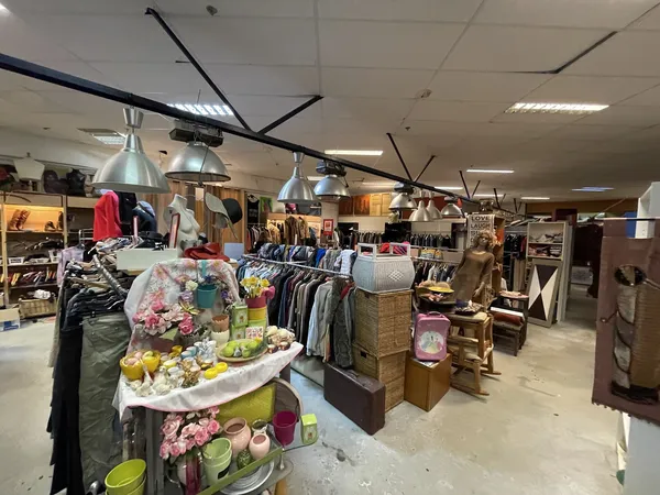 Winkelvloer met kledingrekken, tafels met decoratiespullen en grote ventilators aan het plafond