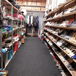 Winkelinterieur met stellingen vol schoenen aan de rechterkant en rekken met kleding en huishoudartikelen aan de linkerkant
