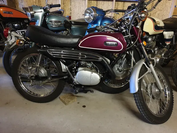 Verzameling van klassieke en vintage motorfietsen in een winkelruimte, waaronder een paarse Suzuki op voorgrond