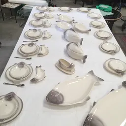 Tafelset met witte serviesgoed en vissen-vormige schalen uitgestald op tafel