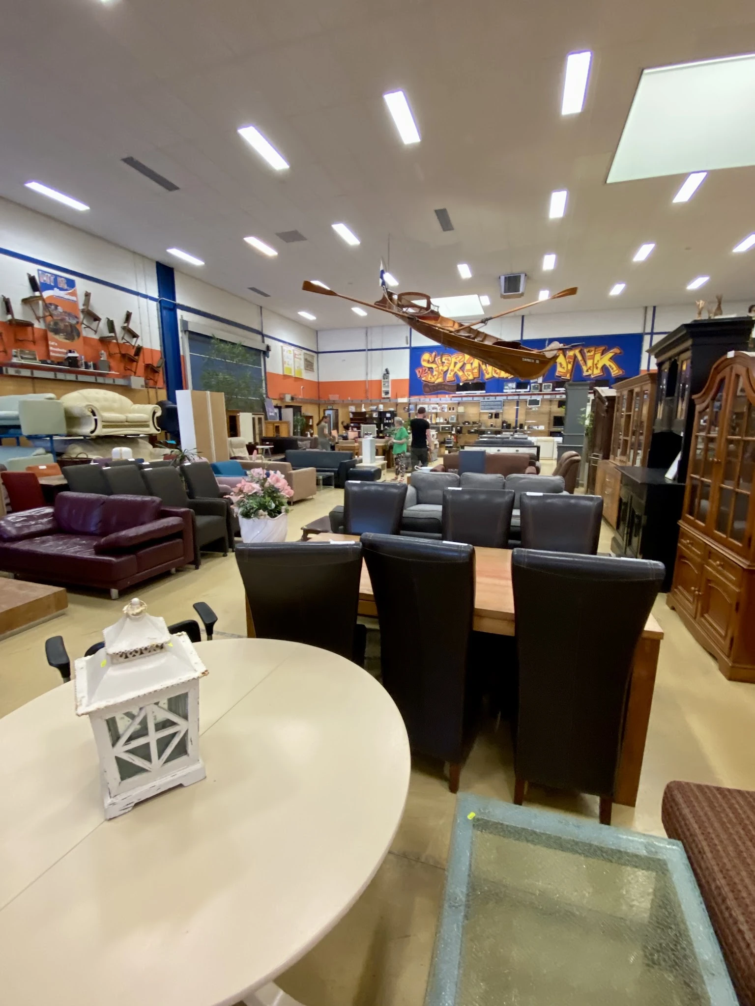Woonwarenhuis met meubels: zwarte stoelen rond tafel, zitbanken, kasten en decorstukken in grote showroom