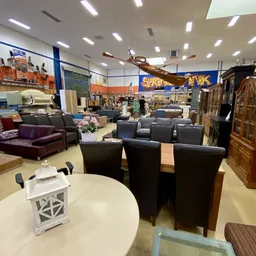 Woonwarenhuis met meubels: zwarte stoelen rond tafel, zitbanken, kasten en decorstukken in grote showroom