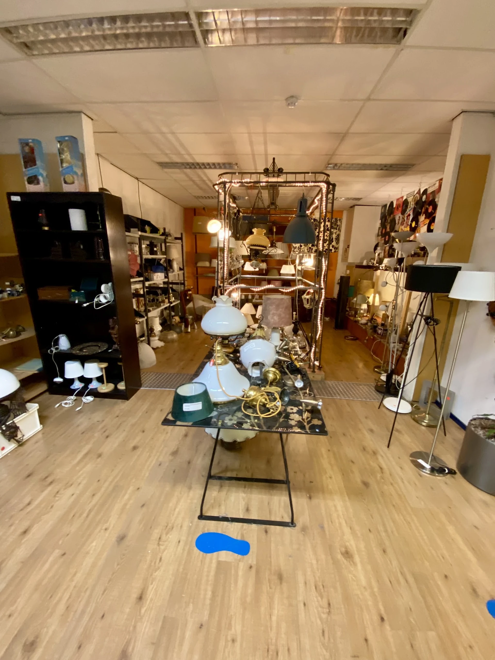 Vintage lampen en kroonluchters uitgestald in de kringloopwinkel, met messing en glazen onderdelen op display