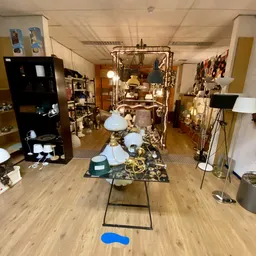 Vintage lampen en kroonluchters uitgestald in de kringloopwinkel, met messing en glazen onderdelen op display