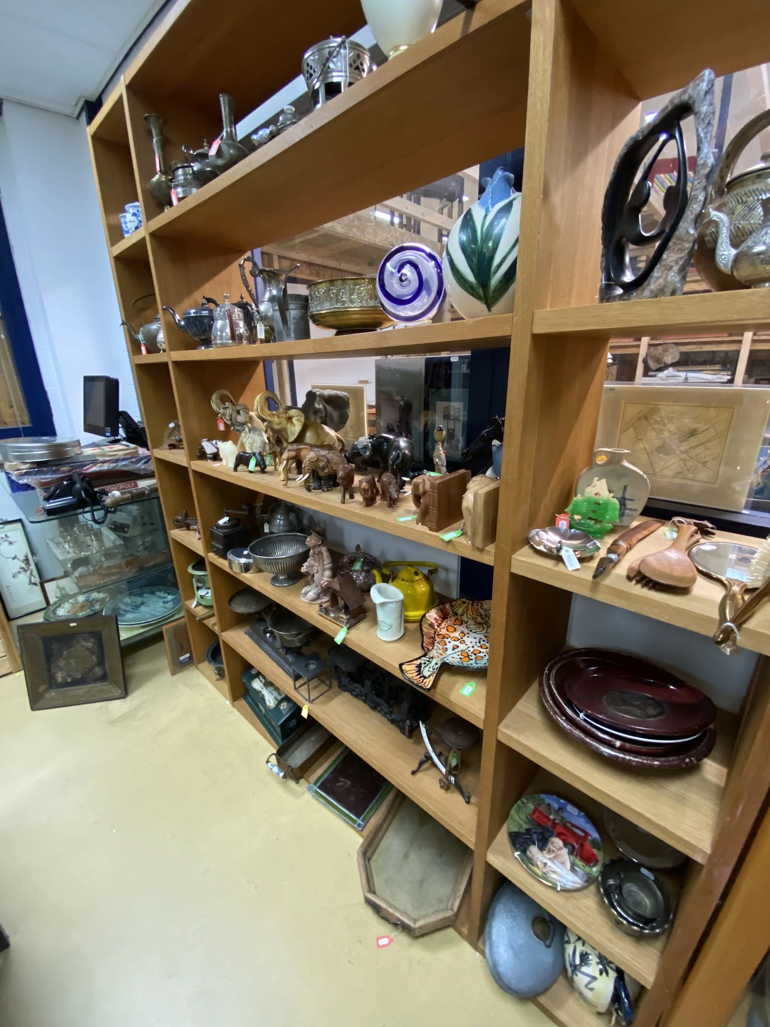 Houten stellingkast gevuld met diverse tweedehands huishoudartikelen, decoratie en gebruiksvoorwerpen