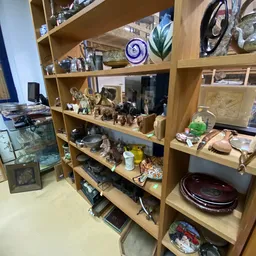 Houten stellingkast gevuld met diverse tweedehands huishoudartikelen, decoratie en gebruiksvoorwerpen