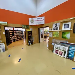 Winkelvloer met boekenkasten, kunstwerken aan muren en diverse spullen in een kringloopwinkel