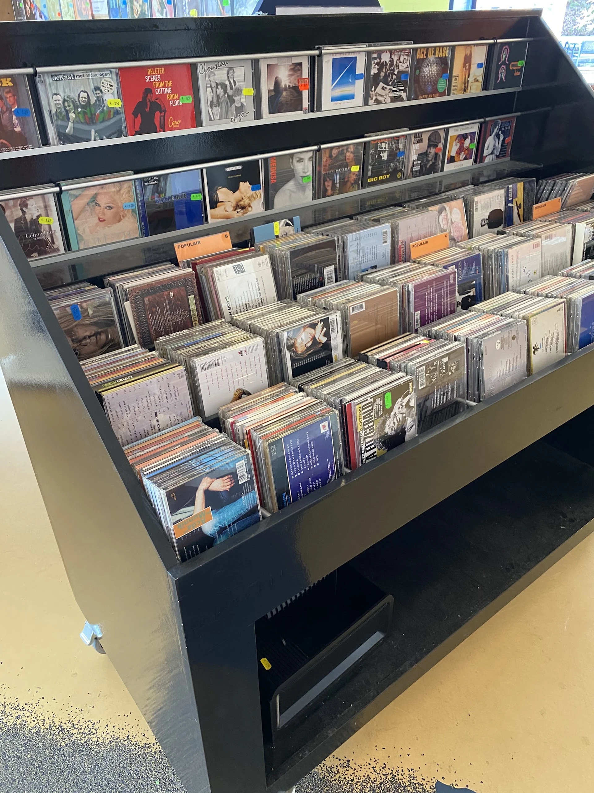 Uitstalling van cd's en dvd's in plastic bakken in een kringloopwinkel