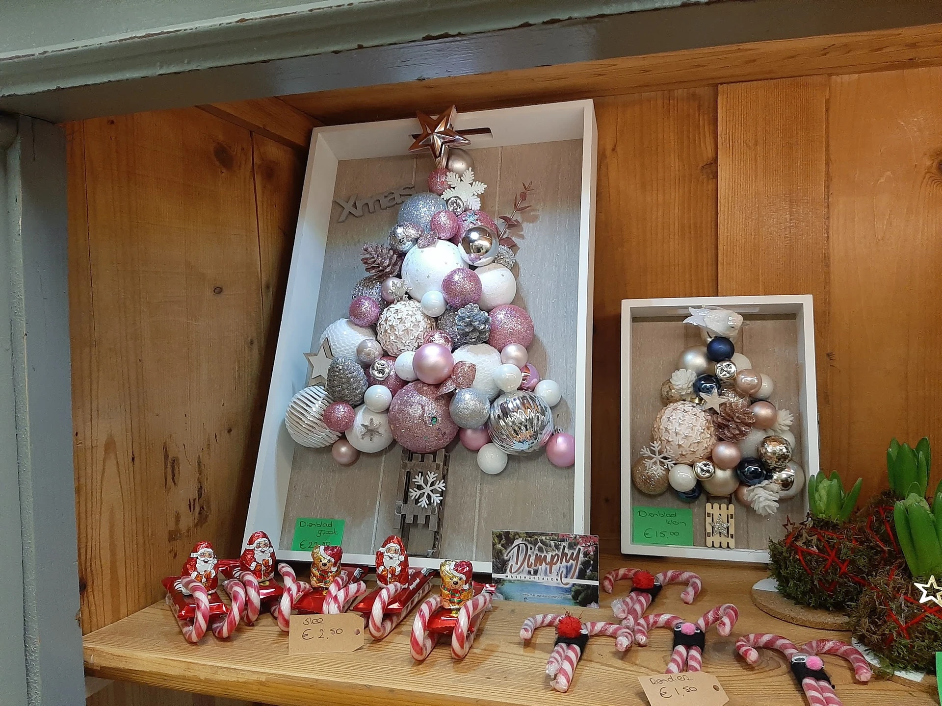 Kerstdecoratie met kerstballen in verschillende kleuren en maten, gesorteerd op houten plank