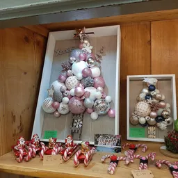 Kerstdecoratie met kerstballen in verschillende kleuren en maten, gesorteerd op houten plank