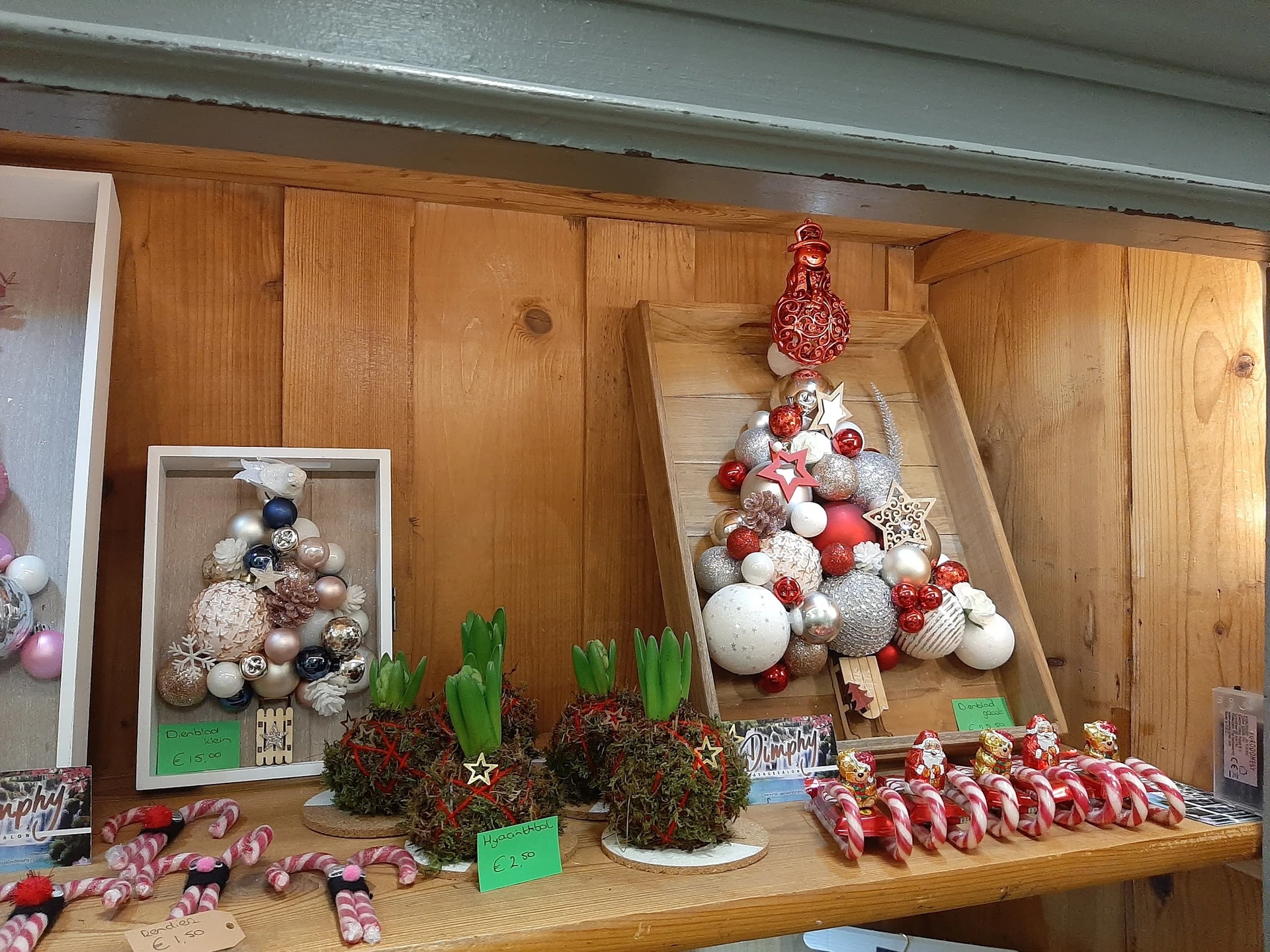 Kerstdecoratie-uitstalling met kerstballen, kerstbomen en versiering op houten planken