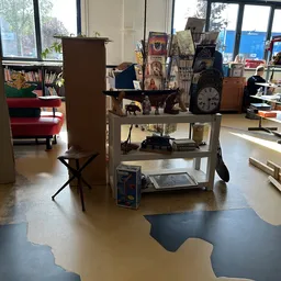 Winkelvloer met stellingen, decoratieve items, klok en meubels in kringloopwinkel