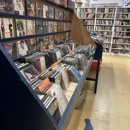 Vitrine met uitgestalde cd's en dvd's, op de achtergrond boekenkasten met dvd-verzameling