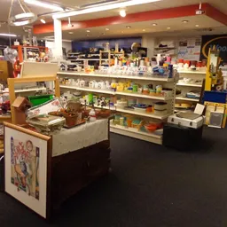 Winkelvloer van kringloopwinkel met verschillende afdelingen, stellingen met huishoudartikelen en displayed merchandise