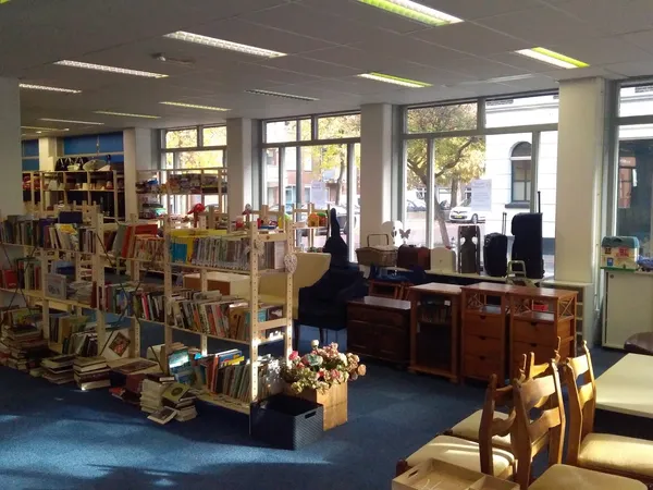Winkelvloer met boekenrekken, zithoeken en grote ramen aan de voorkant van de kringloopwinkel