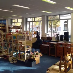 Winkelvloer met boekenrekken, zithoeken en grote ramen aan de voorkant van de kringloopwinkel