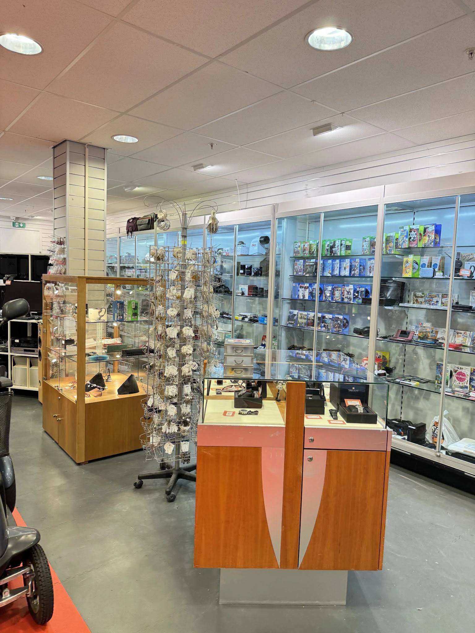 Winkelbinnenruimte met glazen vitrines, houten displaykasten en wandkasten vol met diverse artikelen