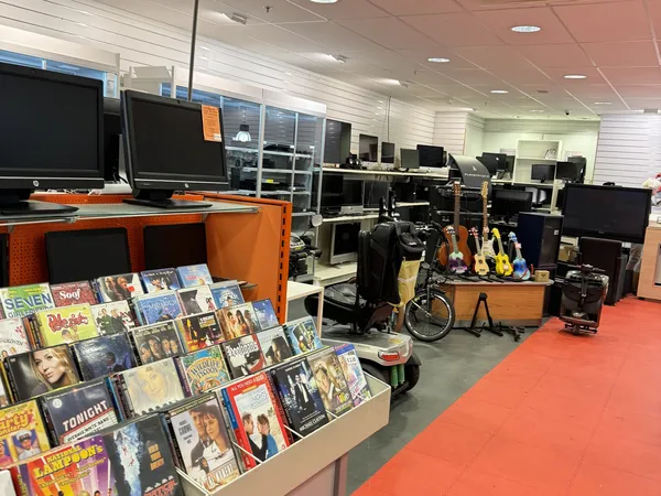Winkelvloer met oranje banden, DVDs en boeken uitgestald, computers en instrumenten in het achtergrondgedeelte