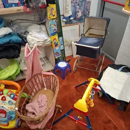 Speelgoed en babyartikelen zoals een wandelwagen, plastic speeltjes en manden op de winkelvloer
