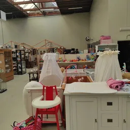 Winkelinterieur met kindermeubels, speelgoed en textiel op tafels en stellingen