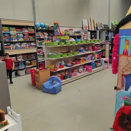 Overzicht van een winkelruimte met stellingen vol speelgoed, spellen en diverse goederen, met groene opbergkubussen op schapp