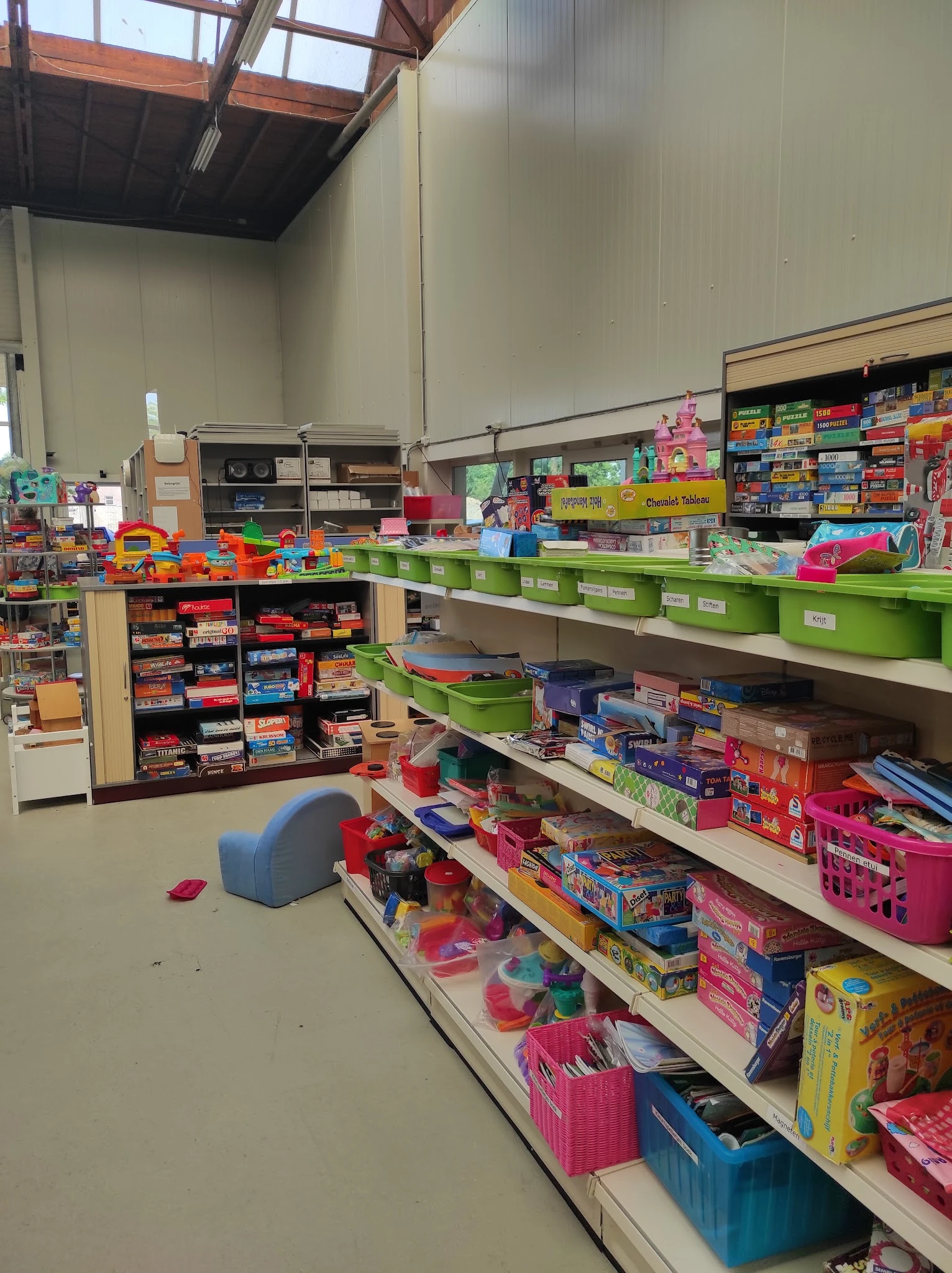 Stellingen vol gekleurde plastic dozen en speelgoed in een kringloopwinkel