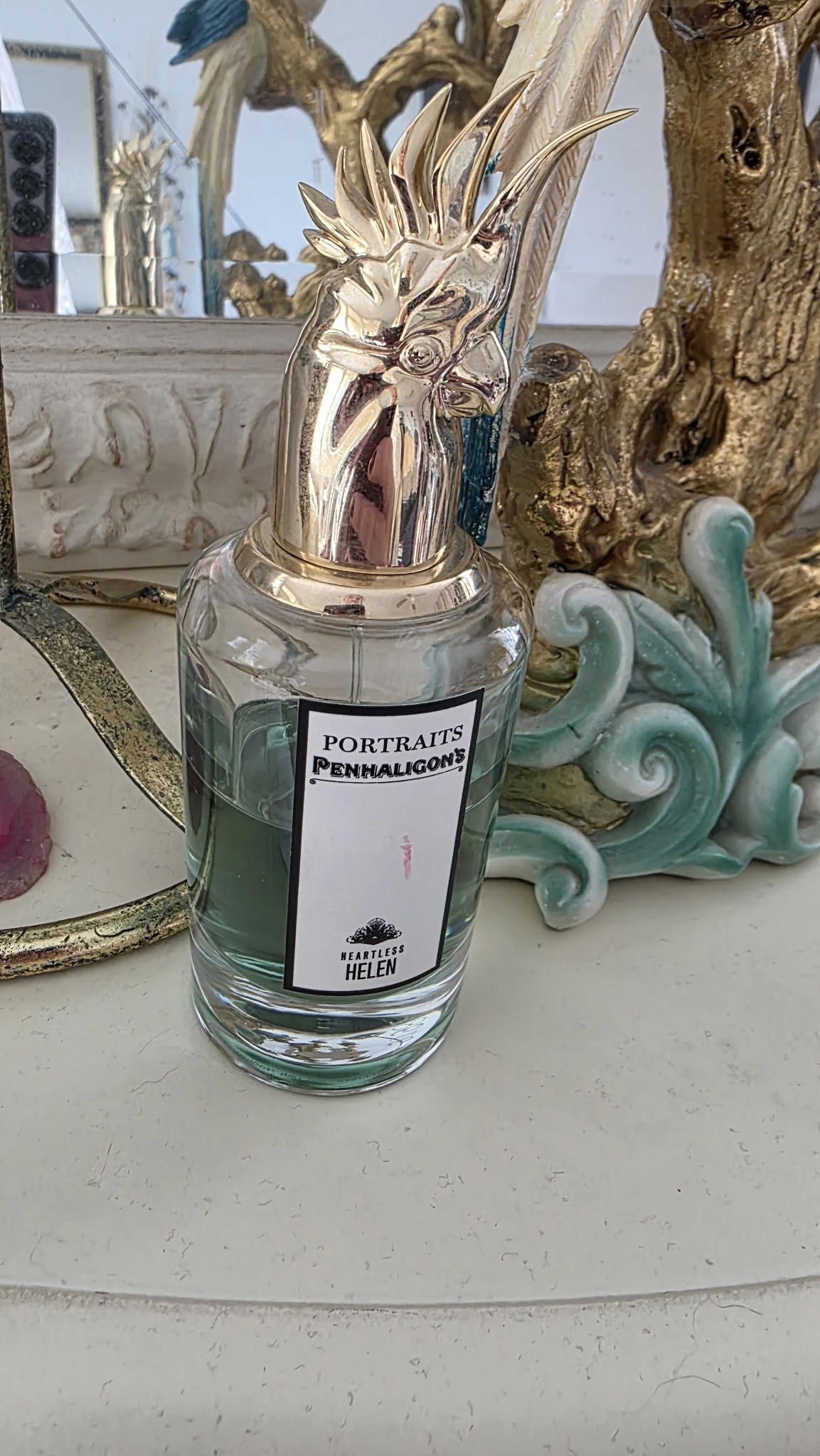 Glazen fles met zilveren dop en etiket 'Portraits Penhaligons', omgeven door decoratieve objecten