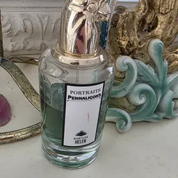 Glazen fles met zilveren dop en etiket 'Portraits Penhaligons', omgeven door decoratieve objecten