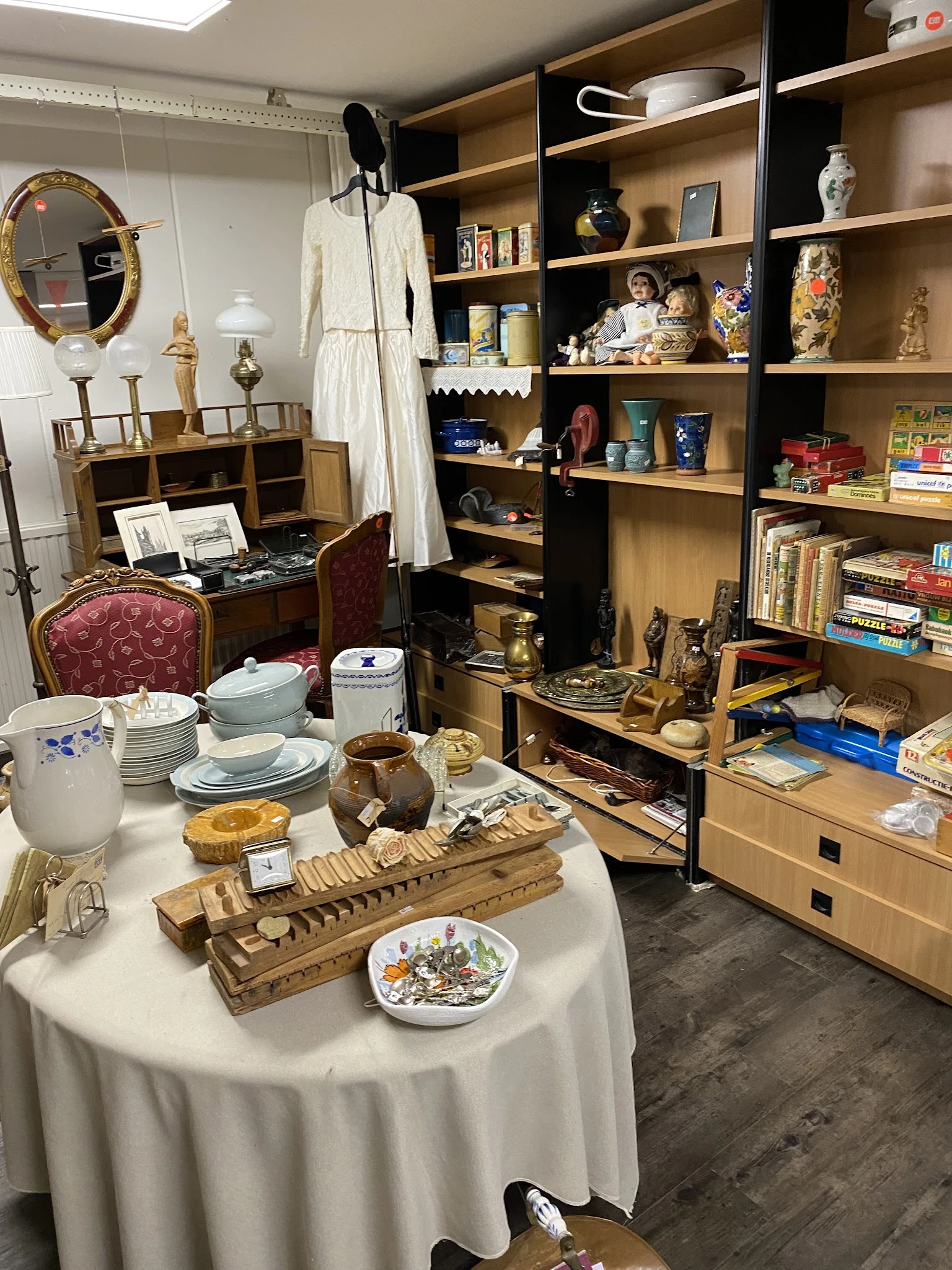 Uitstalling van diverse huishoudelijke artikelen: servies, bestek, houten snijplanken, decoratieve items en boeken in kasten 