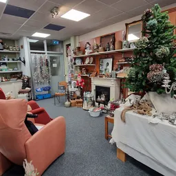 Winkelbinnenruimte met rode fauteuils, houten stellingen vol decoratiespullen, planten en diverse gebruiksartikelen