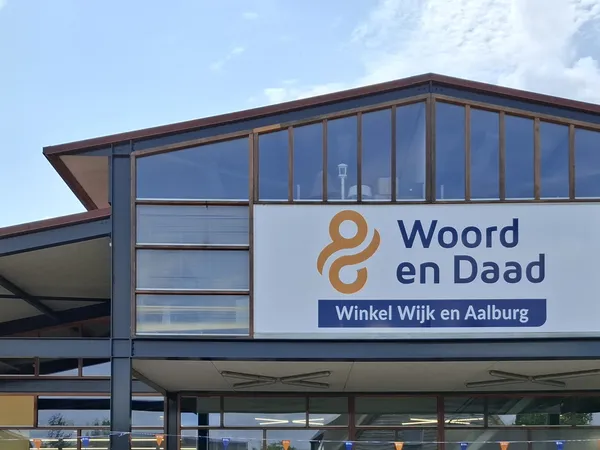 Moderne gevel van kringloopwinkel met groot logo en winkelnaam op wit paneel