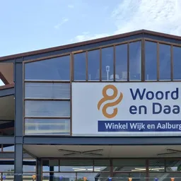 Moderne gevel van kringloopwinkel met groot logo en winkelnaam op wit paneel