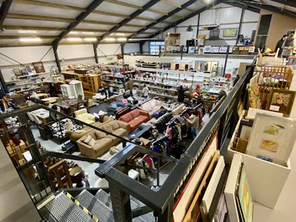 Overzicht van de winkelvloer met diverse meubels, kleding en huishoudartikelen, gezien vanaf een verhoogd platform