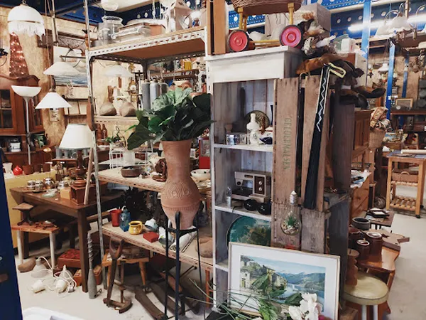 Overzicht van kringloopwinkelinterieur met meubels, lampen, plantenstandaard en diverse huishoudelijke artikelen
