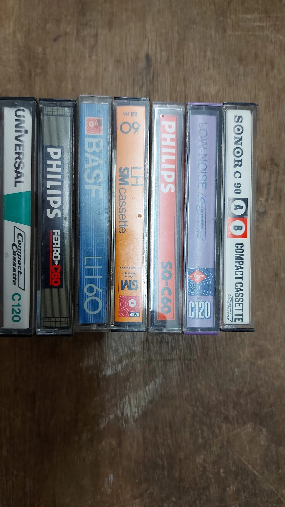 Rij van cassettebandjes in plastic hoezen op houten ondergrond