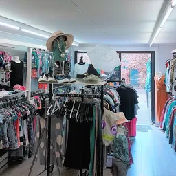 Winkelvloer met rekken tweedehands kleding, mannequin met hoed en hoed, brede doorgang