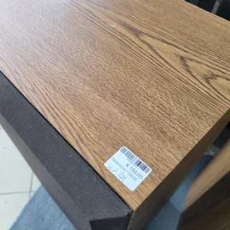 Houten tafel of meubel met prijssticker, grijs stoffen zijpaneel zichtbaar