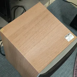 Houten kast of kastje met lichte houtnerf en zwarte onderkant op gekleurde vloer