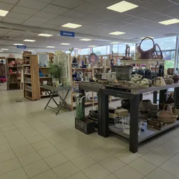 Winkelvloer van een kringloopwinkel met stellingen, toonbanken en diverse tweedehandsartikelen zoals meubels, huishoudspullen