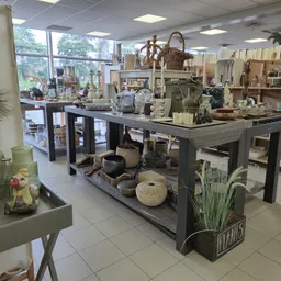 Winkelvloer van kringloopwinkel met tafels vol huishoudelijke artikelen, decoratie en meubelstukken